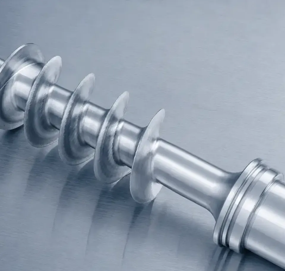 Eine Nahaufnahme einer glänzenden Metallschnecke, die für den Einsatz in Industriemaschinen bestimmt ist und auf einer glatten Metalloberfläche liegt.